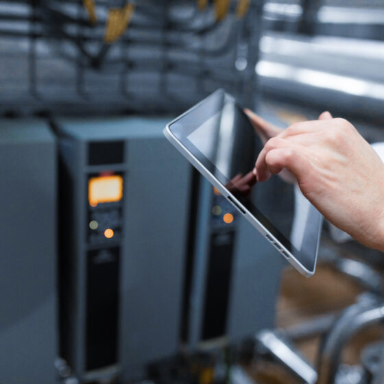 technologist with grey tablet in his hands make a set up of the production line while standing at the department of dairy factory